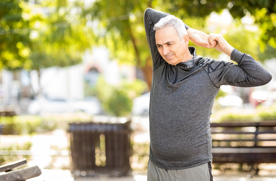 Healthy Middle Aged Man Doing Arms Stretching Workout In The Par